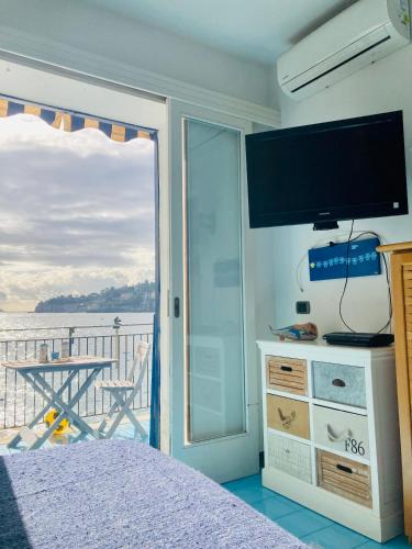 a bedroom with a bed and a balcony with a television at La Perla di Posillipo in Naples