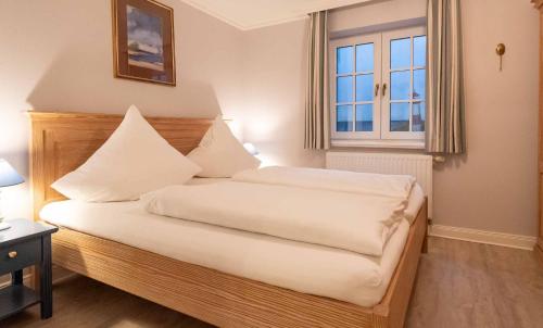 1 dormitorio con 1 cama con sábanas blancas y ventana en LH Isernhagenhof, App 1, en Wenningstedt