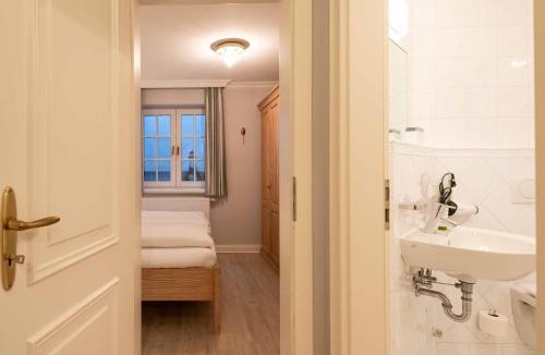 a small bathroom with a sink and a bed at LH Isernhagenhof, App 1 in Wenningstedt