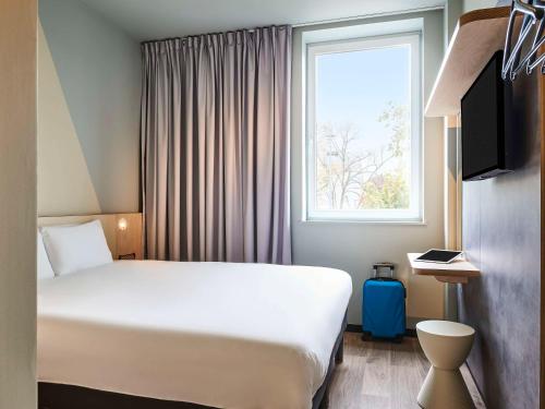 a hotel room with a bed and a window at ibis budget Epinal in Épinal