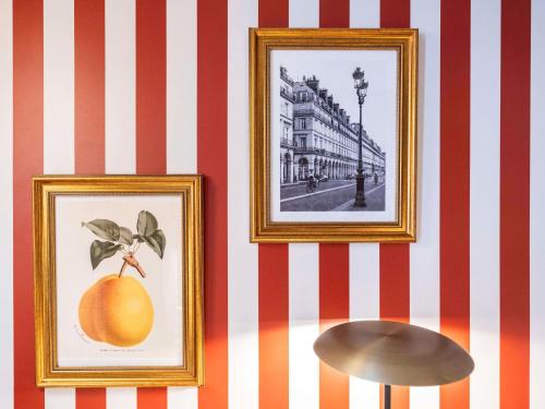 two framed pictures of an orange on a wall at Mercure Paris Notre Dame Saint Germain des Prés in Paris