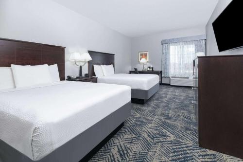 a hotel room with two beds and a window at La Quinta by Wyndham Tulsa Airport / Expo Square in Tulsa