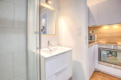een witte badkamer met een wastafel en een magnetron bij L'Esméralda en coeur de ville in Périgueux