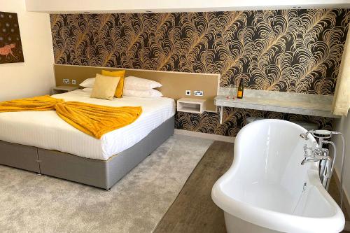 a bedroom with a bed and a tub and a sink at Damon’s Hotel in Lincoln