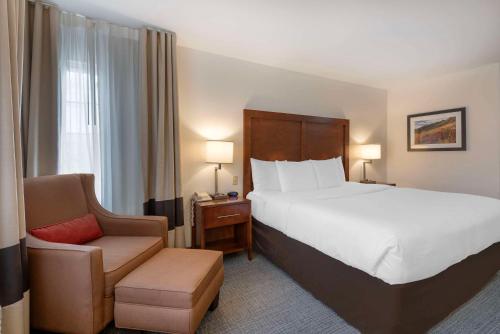 Comfort Inn & Suites Carbondale on the Roaring Fork في كاربوندال: غرفة فندقية بسرير كبير وكرسي