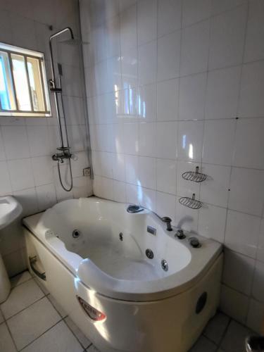 a bath tub in a white tiled bathroom at Entire 3 Bedroom Bungalow - Home away from home in Lagos