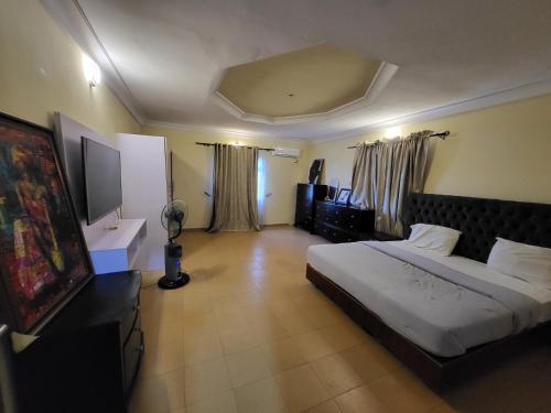 Entire 3 Bedroom Bungalow - Home away from home في لاغوس: غرفة نوم فيها سرير وتلفزيون