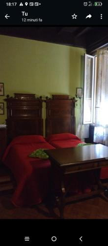 a bedroom with two beds with red sheets and a table at B&B Amarantha Gothica Genoa in Genova