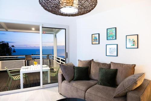 sala de estar con sofá y balcón en "La Ravine" privé, luxe, avec une vue unique en Saint-Joseph