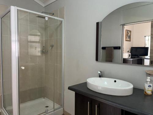 a bathroom with a glass shower and a sink at La Belle Guesthouse Parys in Parys