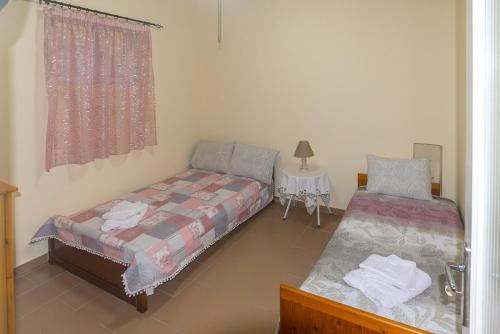 a bedroom with two beds and a table and a window at TAVARI HOUSE in Tavari