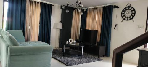 un salon avec une chaise bleue et une télévision dans l'établissement Bloomfields Residences, à Balintiouac