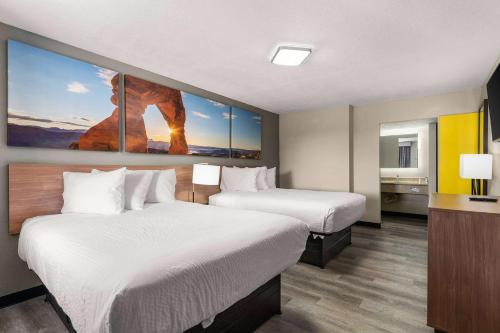 アルバカーキにあるDays inn by Wyndham Albuquerque Northeastのベッド2台が備わる客室で、壁には絵画が飾られています。