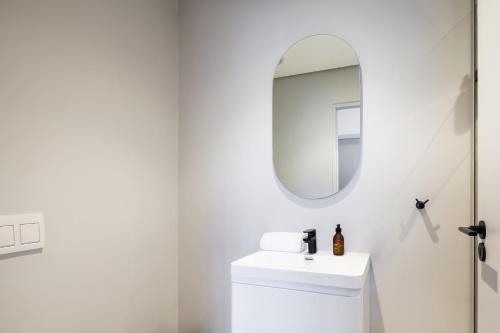 a white bathroom with a sink and a mirror at The Tyne Luxury Apartments in Durban