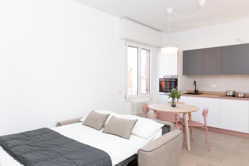 Cet appartement comprend une chambre avec un lit et une table ainsi qu'une cuisine. dans l'établissement New Exclusive Melegnano Apartments- Near train station, à Melegnano