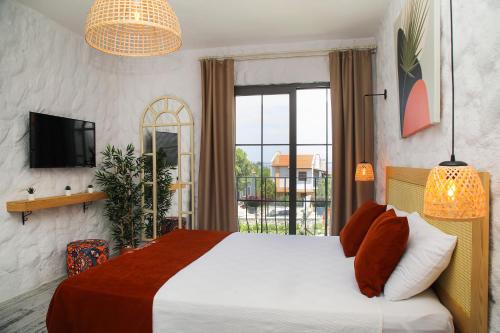 sypialnia z łóżkiem, telewizorem i oknem w obiekcie Huzurla otel w mieście Izmir