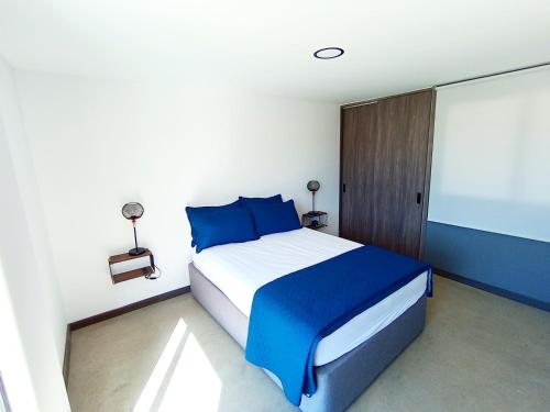 1 dormitorio con cama con almohadas azules y pantalla en Hermosa Villa con piscina, en Los Santos