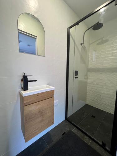 uma casa de banho com um lavatório e um chuveiro com um espelho. em Gold Reef Adelong em Adelong