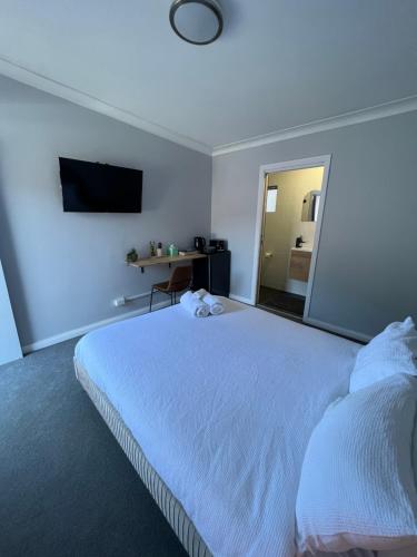 a bedroom with a white bed and a mirror at Gold Reef Adelong in Adelong