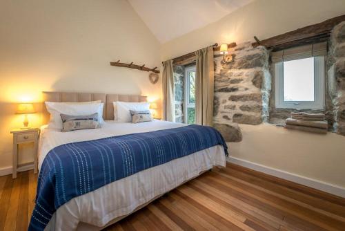 a bedroom with a bed and a stone wall at Stabal-Byrdir in Dyffryn