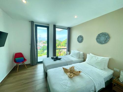 カタビーチにあるBaan Saint-Tropez Seaview Villas Kata Beachのベッド2台と窓が備わるホテルルームです。