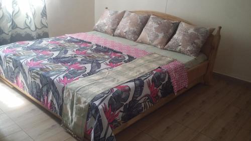 a bed with a colorful blanket and pillows on it at PagersHome Suites- RUSTIC in Kigali
