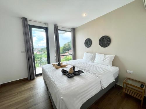 a bedroom with a large white bed with shoes on it at Baan Saint-Tropez Seaview Villas Kata Beach in Kata Beach
