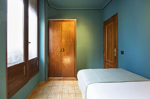 1 dormitorio con 1 cama y puerta de madera en Ideal Hostel Madrid, en Madrid