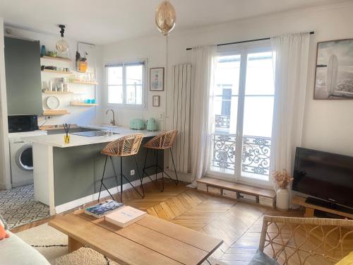 ein Wohnzimmer mit einer Küche und einem Tisch in der Unterkunft Au pied de Montmartre in Paris