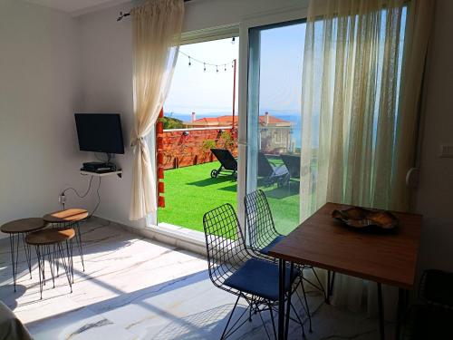 a room with a table and chairs and a large window at Salonikiou Beach Apartments & Villas in Agios Nikolaos