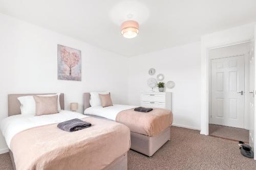 Duas camas num quarto com paredes brancas em Spacious house with 8 beds - convenient location - Whitwell em Peterborough