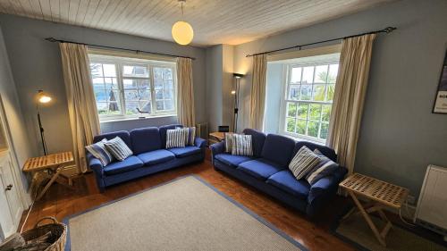 a living room with two blue couches and two windows at Corner Cottage in Saint Mawes