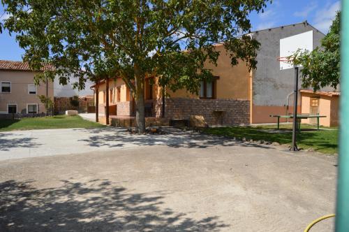 a building with a tree in the middle of a driveway at El Establo,Casa rural in Busto de Bureba