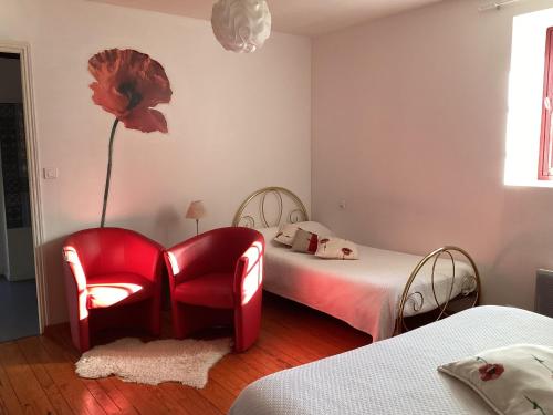 a bedroom with a red chair and a flower on the wall at La Grange in Nohant-Vic