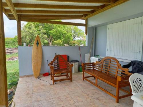 une terrasse avec 2 bancs en bois et une planche de surf dans l'établissement Cottage chaleureux avec jacuzzi, à Saint-François