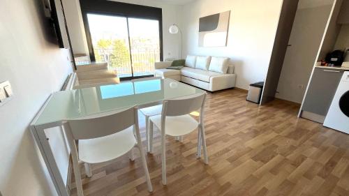 uma cozinha e sala de estar com uma mesa de vidro e cadeiras em Dúplex con terraza by Prestigi em Terrassa