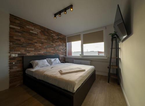 um quarto com uma cama e uma parede de tijolos em No. 2 Comfy center apartment em Klaipėda