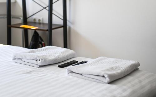 uma cama com duas toalhas e um controlo remoto em No. 2 Comfy center apartment em Klaipėda