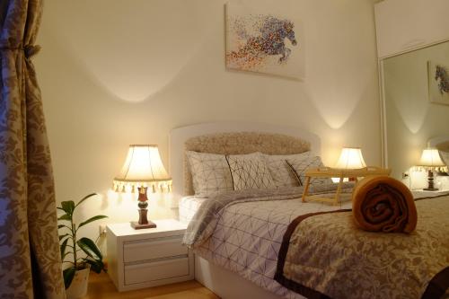 a bedroom with a bed and two lamps on tables at Ameri Plaza Green Apartments in Tbilisi City