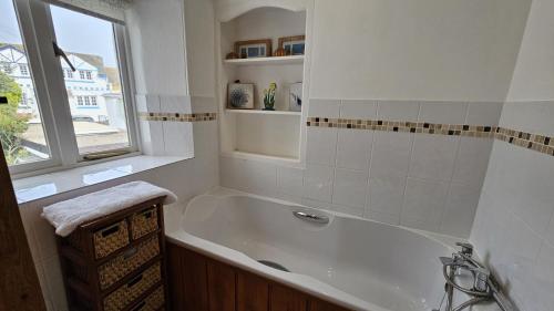 uma banheira branca na casa de banho com uma janela em Hillside Cottage em Porthscatho