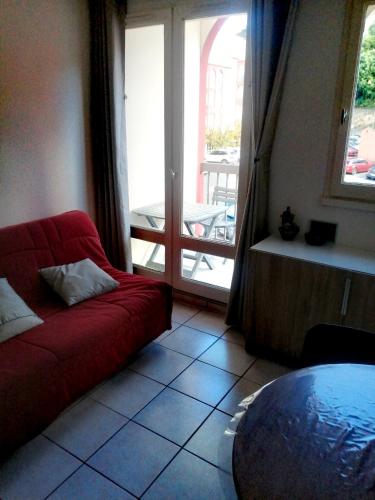 a living room with a red couch in front of a door at Le petit soleil in Lamalou-les-Bains