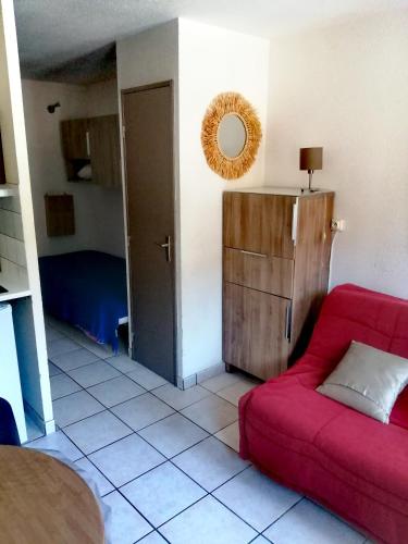 a living room with a red couch and a mirror at Le petit soleil in Lamalou-les-Bains