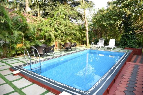 a swimming pool with chairs and a table at 4BHK Private Pool villa in North Goa and Kayaking nearby!! in Moira