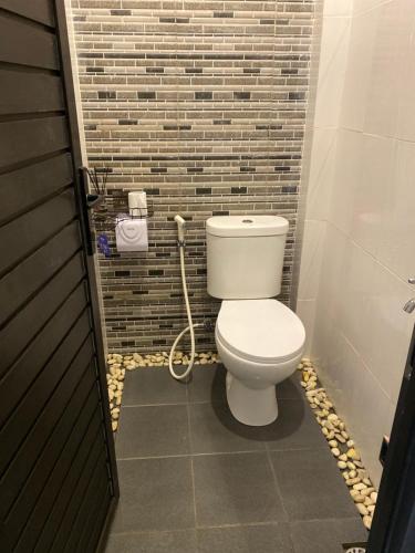 a bathroom with a toilet and a brick wall at Queens Villa in Seminyak