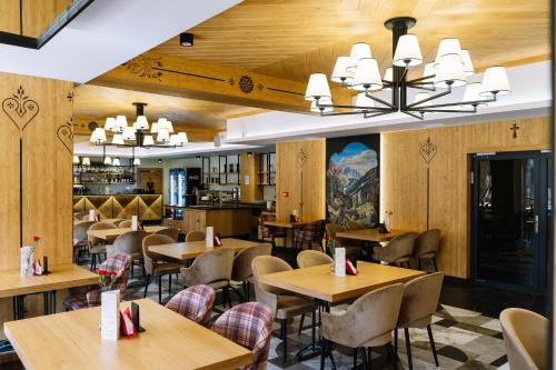 a restaurant with wooden walls and tables and chairs at Hotel Maria & Spa in Szczawnica