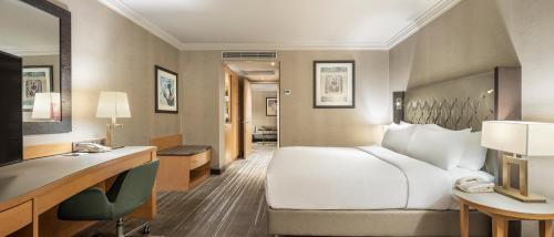 a hotel room with a white bed and a desk at Ankara HiltonSA in Ankara