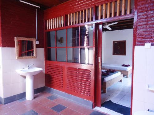 baño con puerta roja y lavamanos en Argasoka Bungalows, en Ubud