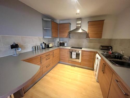 a kitchen with wooden cabinets and a counter top at Deluxe Large Apartment Opposite Hepworth Gallery in Wakefield