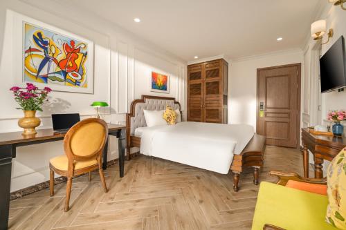 a bedroom with a bed and a desk with a computer at Maison Fleur Luxury Hoi An in Hoi An