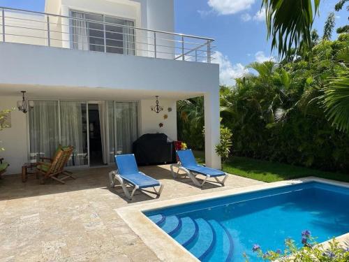 a house with a swimming pool and two blue chairs at Villa hermosa en Playa Nueva Romana in San Pedro de Macorís
